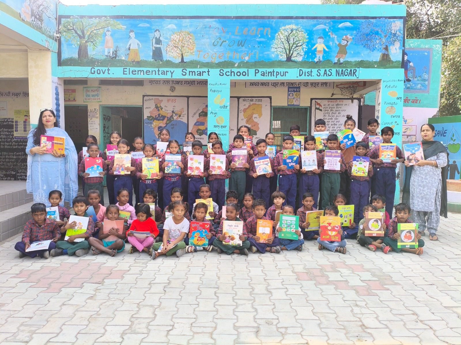 Children holding donated books at Government Elementary Smart School Paintpur